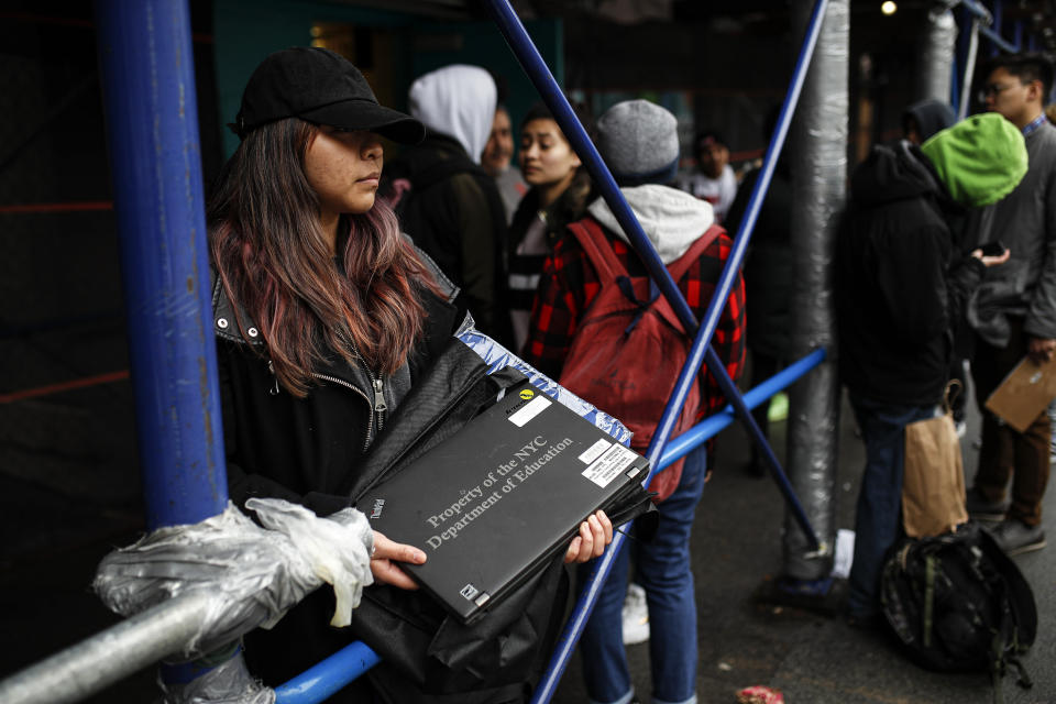 Anna Louisa, 18, receives her school laptop for home study at the Lower East Side Preparatory School, Thursday, March 19, 2020, in New York, as coronavirus restrictions shuttered classrooms throughout the city. New York Gov. Andrew Cuomo tightened work-from-home rules as confirmed cases continued to climb in New York, an expected jump as testing becomes more widespread. (AP Photo/John Minchillo)