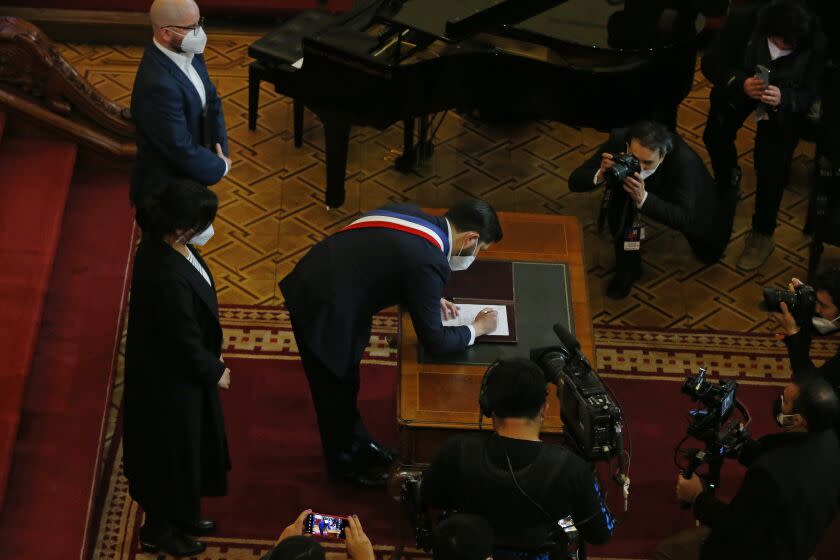 Chilean President Gabriel Boric signs a document that calls for a referendum on the approval or rejection of the country's new constitution during a ceremony at the former Congress in Santiago, Chile, Monday, July 4, 2022. Chileans elected an assembly to write fresh governing principles and put them to a national vote in 2022 with the goal of a more inclusive country and the erasure of a relic of military rule. (AP Photo/Luis Hidalgo)