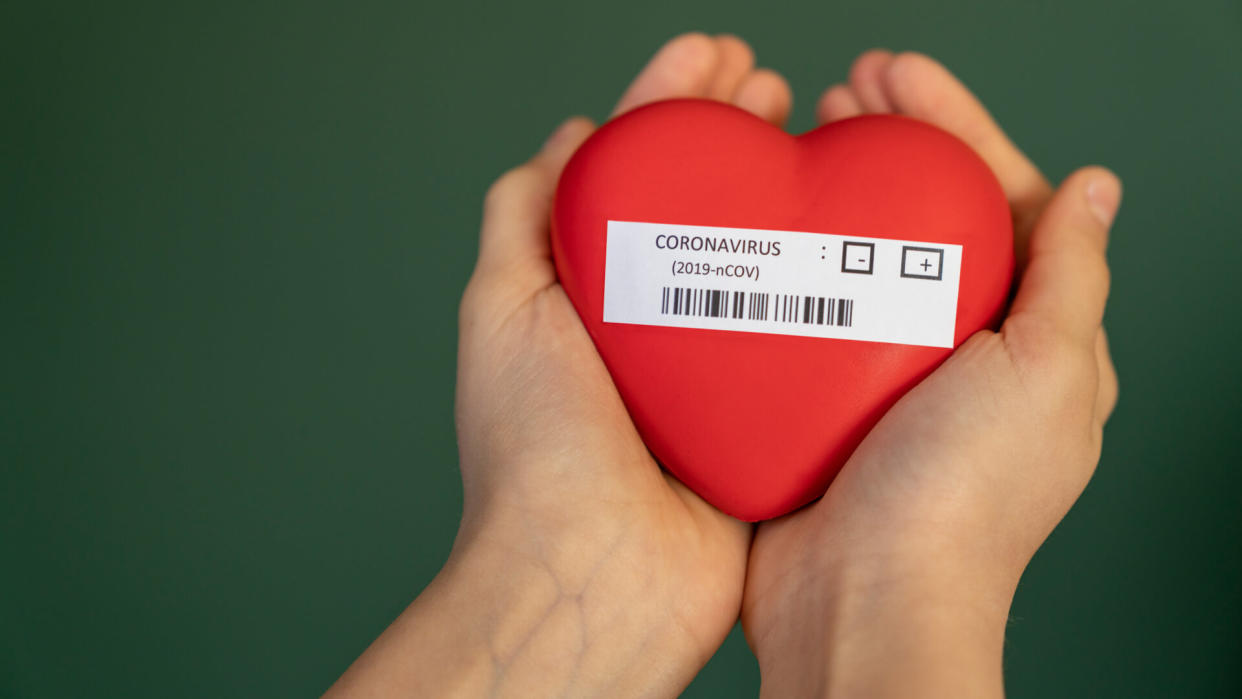 girl holding coronavirus written heart shape in her hand.