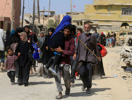 A displaced Iraqi man who fled from clashes, carries a woman in western Mosul, Iraq, June 3, 2017. REUTERS/Alaa Al-Marjani