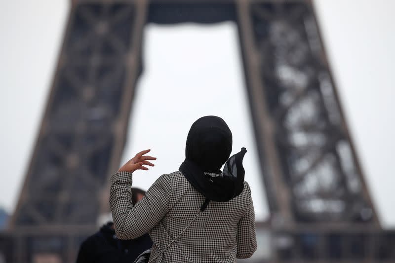 A woman wearing a hijab walks at Trocadero square near the Eiffel Tower in Paris