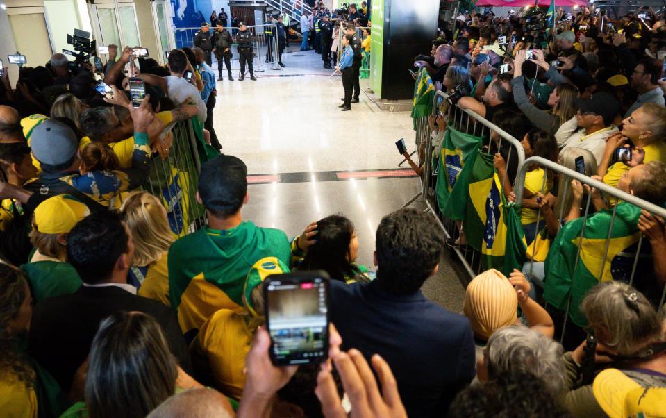 Supporters with Brazil flags wait for Mr Bolsonaro to exit the arrivals area - Andressa Anholete/Getty Images South America