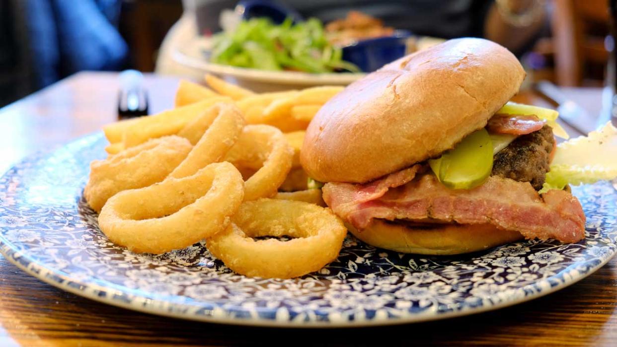  A JD Wetherspoons Ultimate Burger meal served with onion rings and chips. 