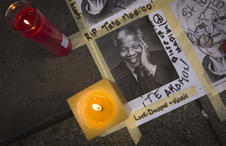 Candles and photos are placed on the ground as part of a makeshift vigil outside the Apollo Theatre in memoriam to the late Nelson Mandela in the Harlem area of New York December 6, 2013. REUTERS/Carlo Allegri