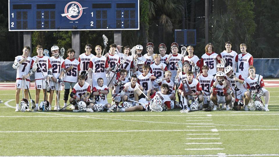 The Oxbridge Academy boys lacrosse team poses with their district title trophy following the team's 11-4 victory over visiting St. John Paul II on Thursday night on April 14, 2022.