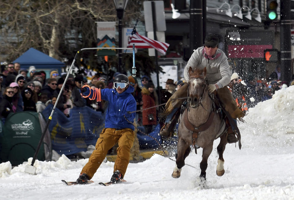 A skijoring team competes in Leadville, Colo., on Saturday, March 2, 2024. Skijoring draws its name from the Norwegian word skikjoring, meaning "ski driving." It started as a practical mode of transportation in Scandinavia and became popular in the Alps around 1900. Today's sport features horses at full gallop towing skiers by rope over jumps and around obstacles as they try to lance suspended hoops with a baton, typically a ski pole that's cut in half. (AP Photo/Thomas Peipert)