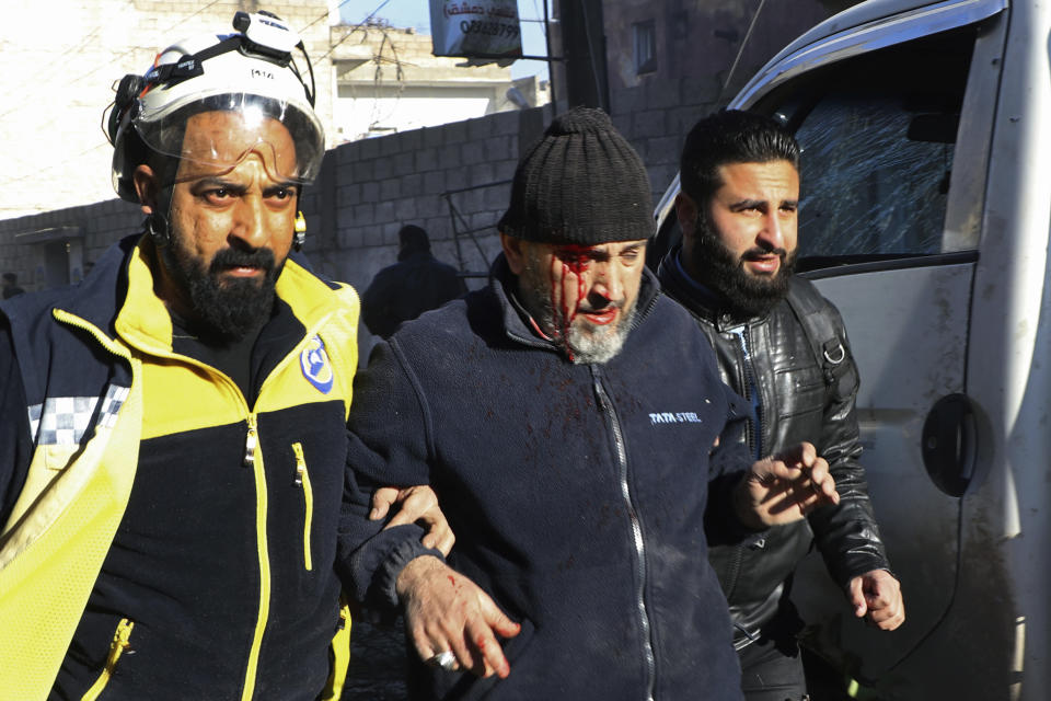 This photo provided by the Syrian Civil Defense White Helmets, which has been authenticated based on its contents and other AP reporting, shows a Syrian White Helmet civil defense worker, left, helping an injured man, in the town of Afrin, north of Aleppo, Thursday, Jan. 20, 2022. The rocket attack on Afrin, controlled by Turkey-backed opposition fighters, killed several civilians and wounded over a dozen people on Thursday, Syrian rescuers and a war monitor said. Both blamed U.S-backed Syrian Kurdish forces for the attack. (Syrian Civil Defense White Helmets via AP)