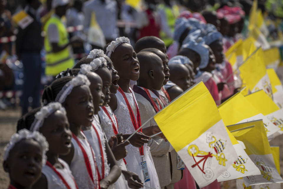 Young girls sing and wave Vatican flags as Pope Francis arrives at the St. Theresa Cathedral in Juba, South Sudan, Saturday, Feb. 4, 2023. Pope Francis is in South Sudan on the second leg of a six-day trip that started in Congo, hoping to bring comfort and encouragement to two countries that have been riven by poverty, conflicts and what he calls a "colonialist mentality" that has exploited Africa for centuries. (AP Photo/Ben Curtis)