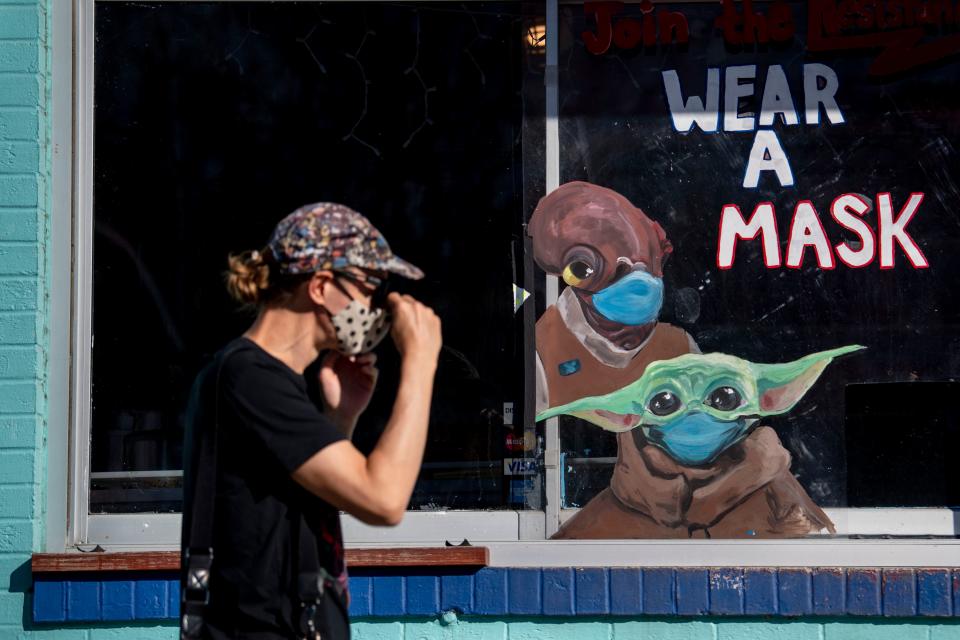 A woman passes a sign advising people to wear their masks outside Amy's Ice Creams in Austin, Texas.