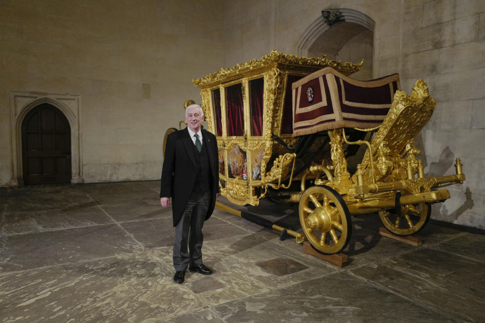 Britain's Speaker of the House of Commons Lindsay Hoyle poses next to the Speaker's State Coach as it returns to Westminster, ahead of the coronation of Britain's King Charles III, in London, Sunday, April 30, 2023. The gilded coach, which was last seen in the historic Westminster Hall in 2005, will be on display once again from 2 May to the Autumn, to commemorate the crowning of King Charles III. (AP Photo/Alberto Pezzali)