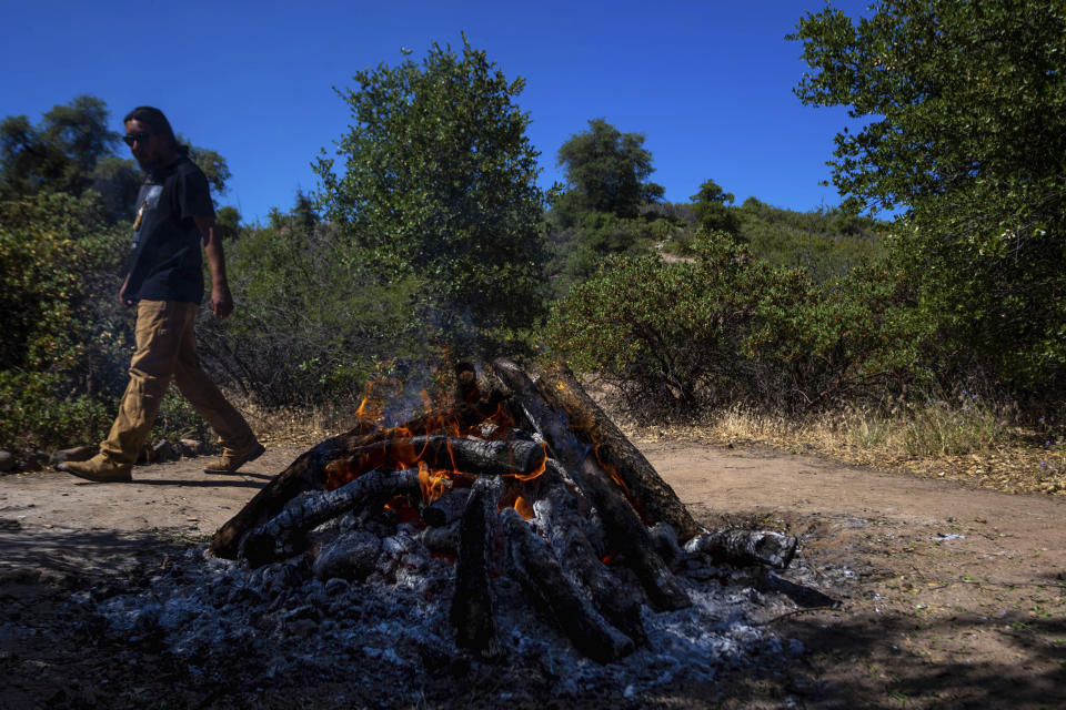 Morgun Frejo checks on rocks being heated in a fire for a sweat lodge on Oak Flat Campground, a sacred site for Native Americans located 70 miles east of Phoenix, on June 3, 2023, in Miami, Ariz. (AP Photo/Ty O'Neil)