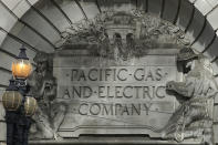 FILE - In this Oct. 10, 2019, file photo, a Pacific Gas & Electric sign is shown outside of a PG&E building in San Francisco. Pacific Gas and Electric says it has reached a $13.5 billion settlement that will resolve all major claims related to devastating wildfires blamed on its outdated equipment and negligence. The settlement, which the utility says was reached Friday, Dec. 6, 2019, still requires court approval. (AP Photo/Jeff Chiu)