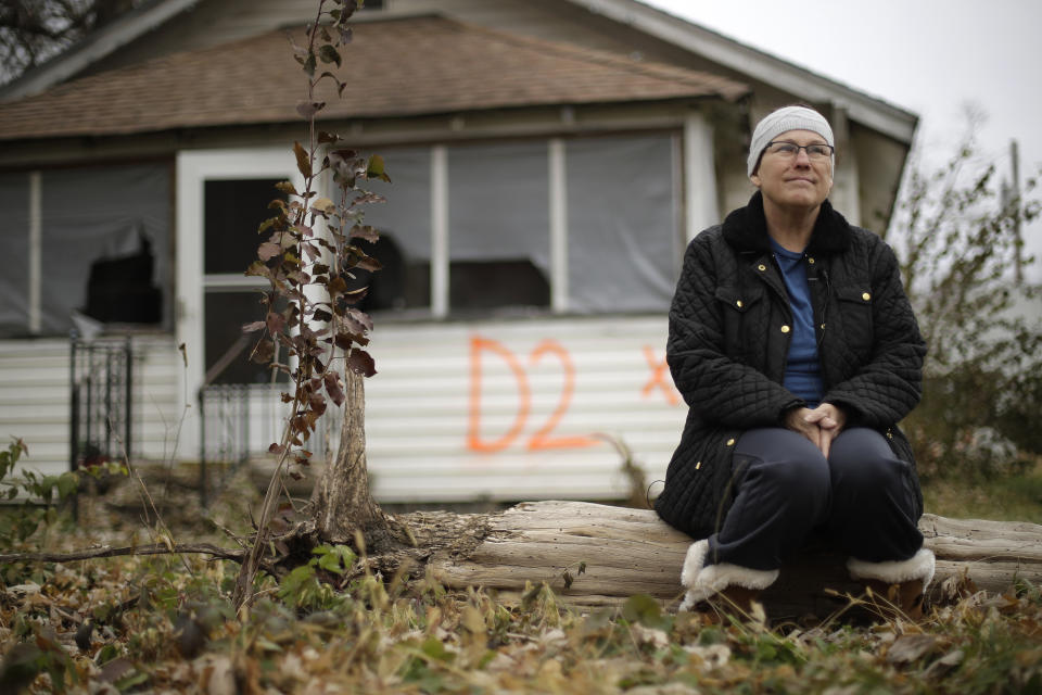 In this photo taken Monday, Nov. 18, 2019, Tammy Kilgore sits in front of her former home in Mosby, Mo. before it was demolished as part of a voluntary buyout program in the flood-prone town. (AP Photo/Charlie Riedel)