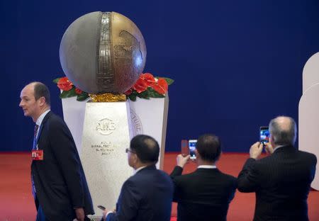 Attendees take smartphone photos of a sculpture following the opening ceremony of the Asian Infrastructure Investment Bank (AIIB) in Beijing, China, January 16, 2016. REUTERS/Mark Schiefelbein/Pool