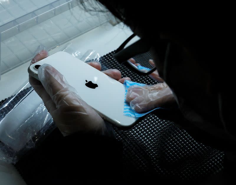 A worker cleans a used iPhone at an operations centre of Belong Inc, in Zama