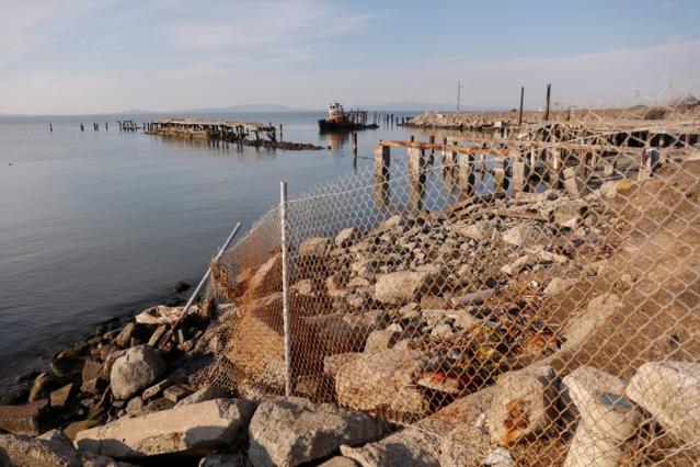 A burned down pier and rusting boat sit at an old sail boat harbor at Lone Tree Point, Rodeo, CA