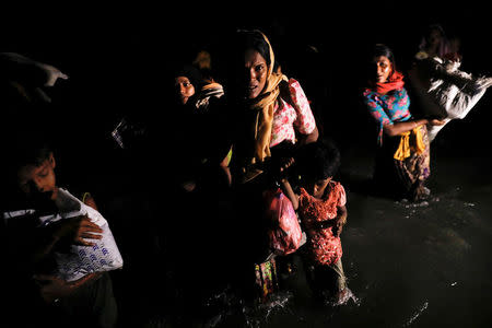 Women and children wade through the water as hundreds of Rohingya refugees arrive under the cover of darkness by wooden boats from Myanmar to the shore of Shah Porir Dwip, in Teknaf, near Cox's Bazar in Bangladesh, September 27, 2017. REUTERS/Damir Sagolj