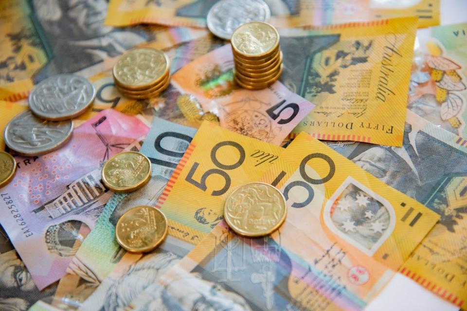 Australia cash note and coin savings sprawled on table to signify interest rate rises.