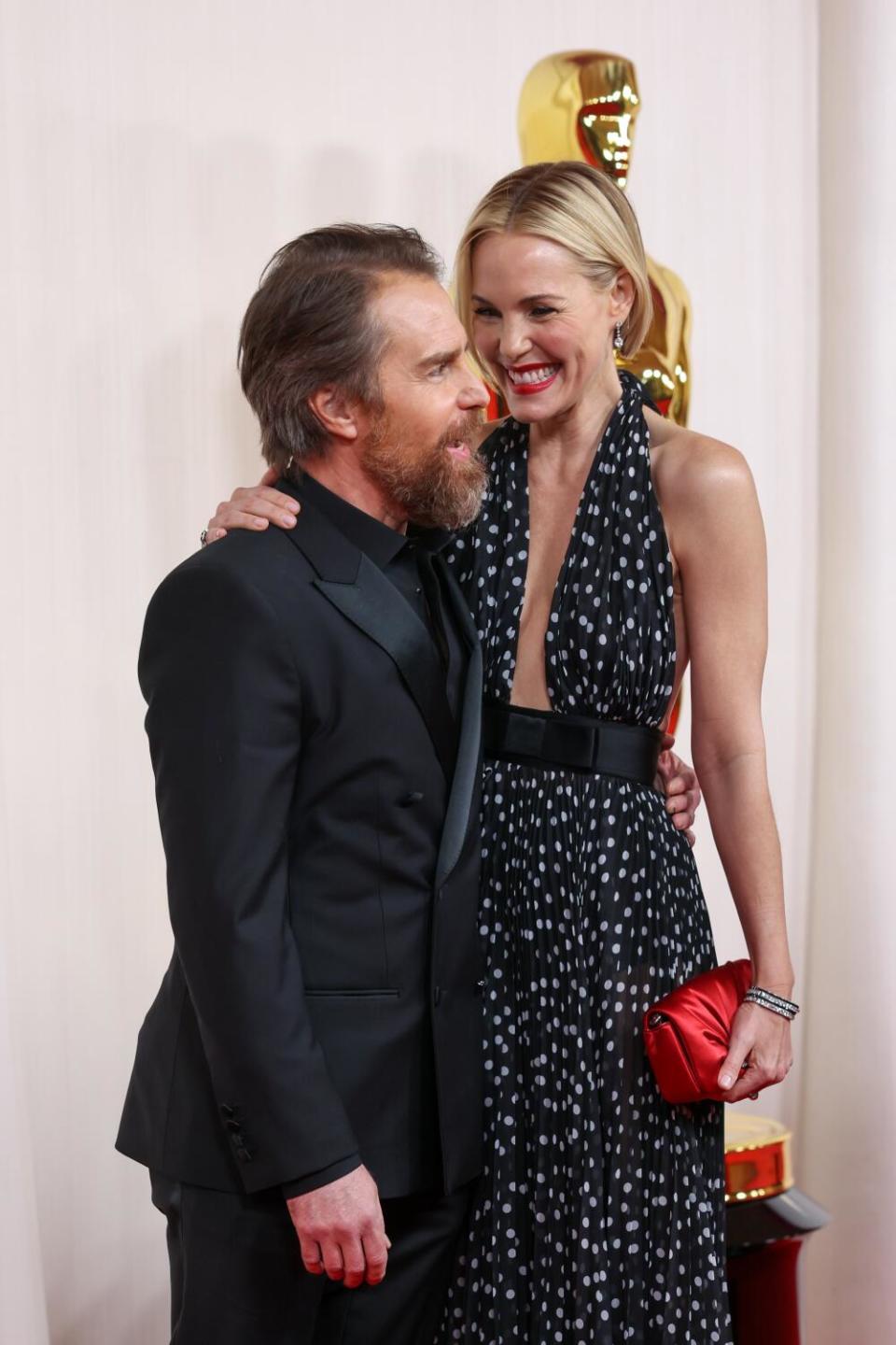 Sam Rockwell and Leslie Bibb, both in black, laugh on the red carpet.