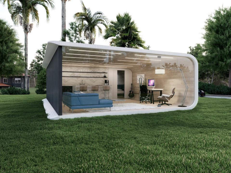 The ADU in a backyard on a patch of grass with palm trees