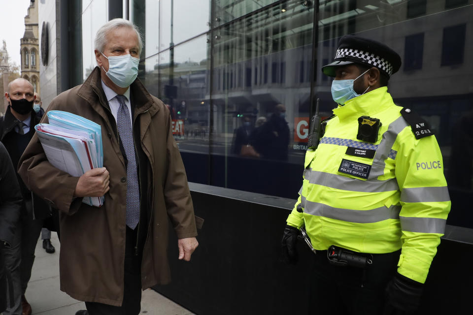 EU Chief Negotiator Michel Barnier passes a Police officer as he walks to a conference centre in Westminster in London, Sunday, Nov. 29, 2020. Teams from Britain and the European Union are continuing face-to-face talks on a post-Brexit trade deal in the little remaining time. (AP Photo/Kirsty Wigglesworth)