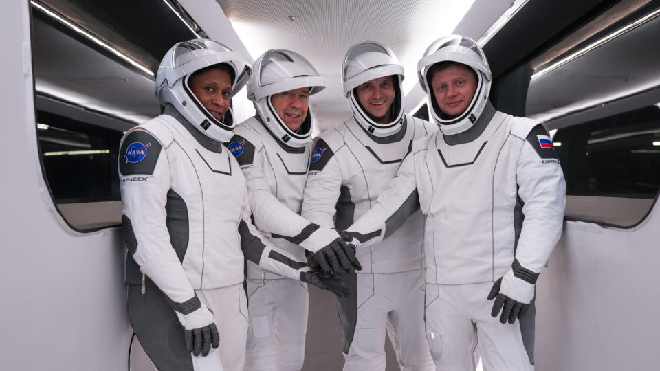 Four Crew-8 astronauts in white SpaceX spacesuits rest their arms before launch.