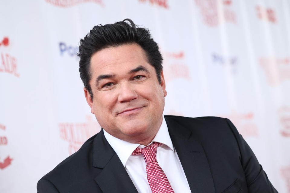 Dean Cain bei einem Event auf dem roten Teppich in einem schwarzen Anzug, einem weißen Hemd und einer rot gepunkteten Krawatte