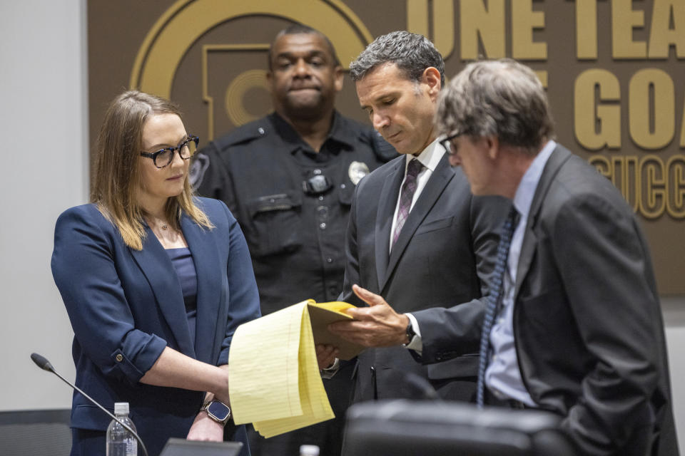 Cobb County teacher Katie Rinderle reviews material with her attorney Craig Goodmark, second from right, during a hearing at the Cobb County Board of Education in Marietta, Ga, Thursday, Aug. 10, 2023. Rinderle is facing termination after reading "My Shadow is Purple," a book about gender identity, to fifth graders. (Arvin Temkar/Atlanta Journal-Constitution via AP)