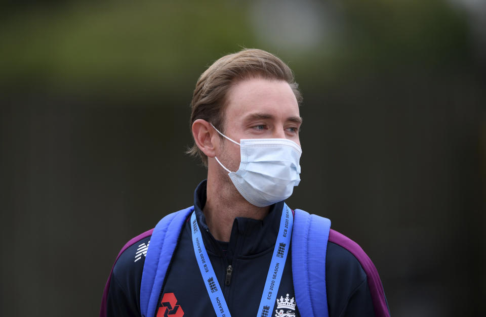 England's Stuart Broad wears a face mask as a precaution against the coronavirus as he watches teammates train before the start of the first day of the 1st cricket Test match between England and West Indies, at the Ageas Bowl in Southampton, England, Wednesday July 8, 2020. (Mike Hewitt/Pool via AP)