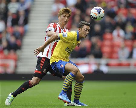 Arsenal's Mesut Ozil (R) is challenged by Sunderland's Ki Sung-Yeung during their English Premier League soccer match at The Stadium of Light in Sunderland, northern England, September 14, 2013. REUTERS/Nigel Roddis