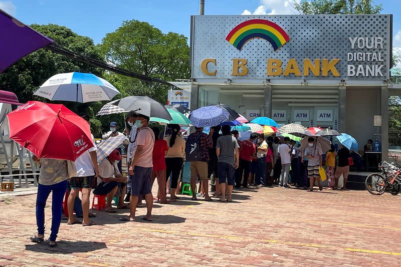 People line up outside a bank to withdraw cash, in Yangon