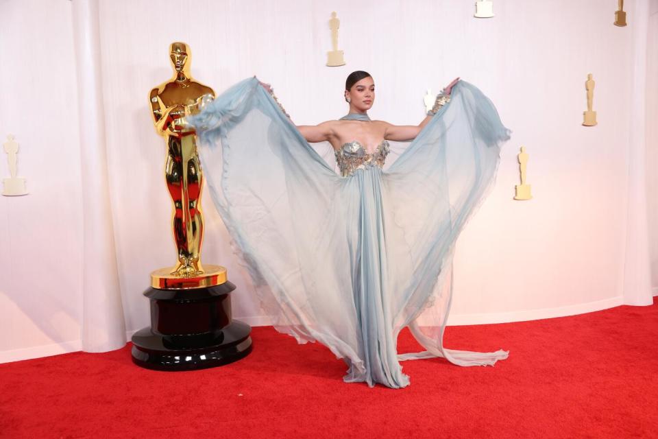 Hailee Steinfeld holds up the skirt of her pale blue dres.