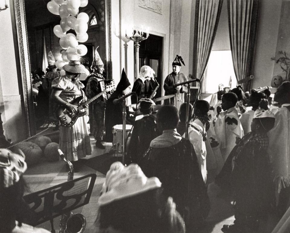 In this photograph, costumed members of the United States Marine Band entertain guests during a Halloween party in the East Room of the White House in 1969. This photograph was taken during the Richard M. Nixon administration.