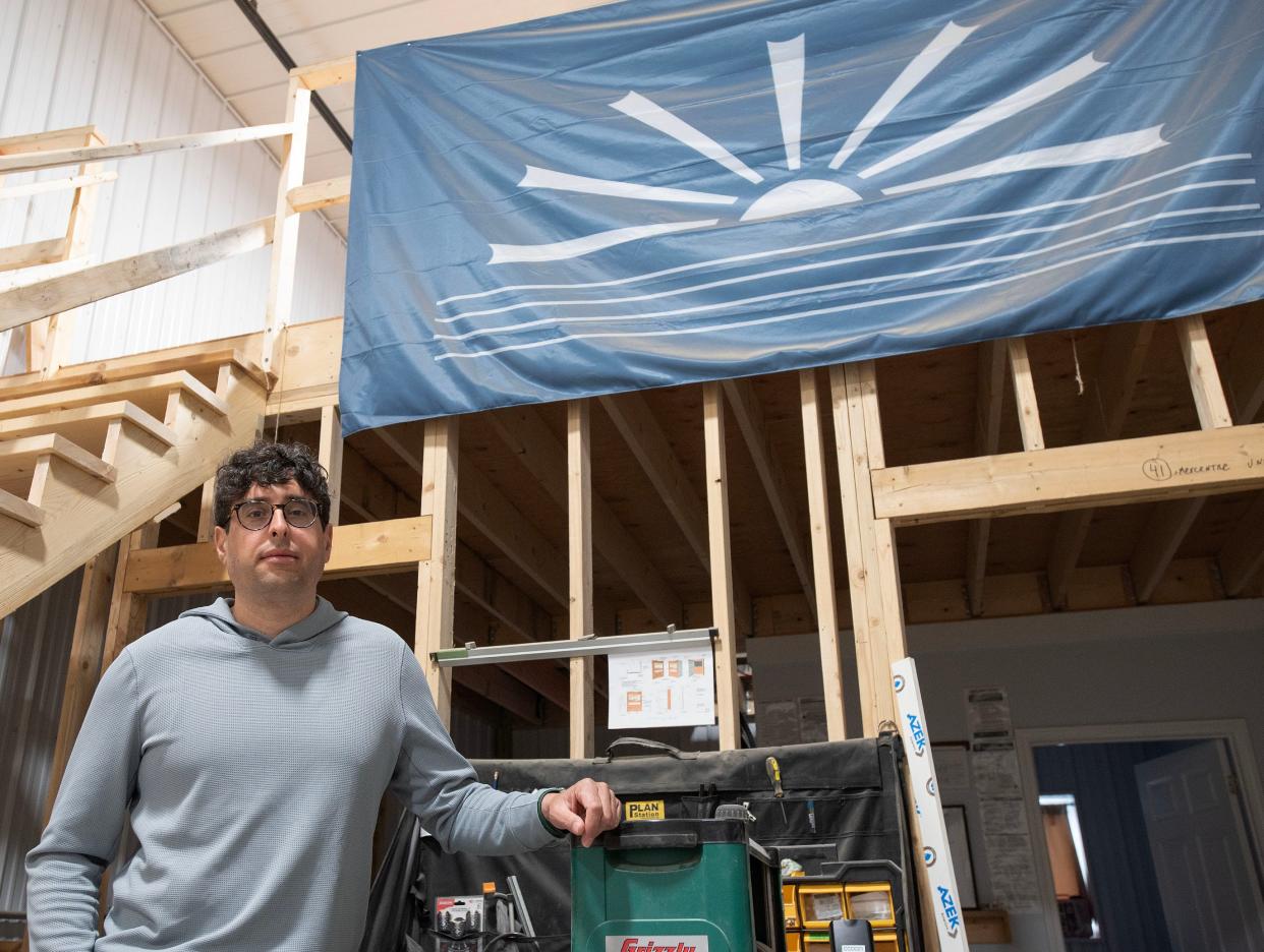 Steve Peters at the SmokeSygnals workshop in Mashpee below a flag the company designed for the Wampanoag Tribe.