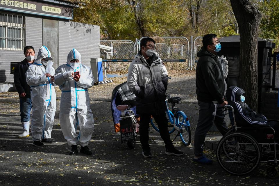 People in personal protective equipment (PPE) and residents wait to be swabbed for the COVID-19 at a testing site in Beijing, China, November 25, 2022. / Credit: JADE GAO/AFP/Getty