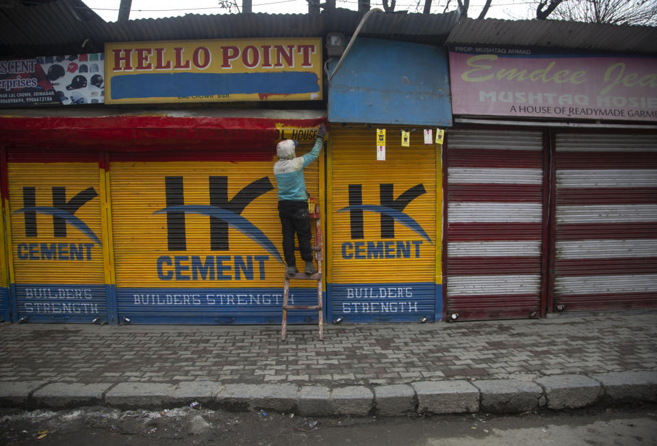 A man paints the exterior of a closed shop in Srinagar, Indian controlled Kashmir, Tuesday, Feb. 9, 2021. Businesses and shops have closed in many parts of Indian-controlled Kashmir to mark the eighth anniversary of the secret execution of a Kashmiri man in New Delhi. Hundreds of armed police and paramilitary soldiers in riot gear patrolled as most residents stayed indoors in the disputed region's main city of Srinagar. (AP Photo/Mukhtar Khan)