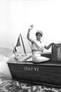 <p>Italian film star Rosanna Schiaffino waves to her fans as she arrives at an event in 1960 via water taxi. The actress sits on the stern of the vessel in a cream two-piece set and floral fascinator. </p>