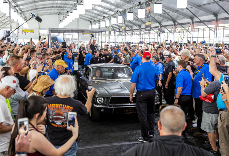 People surround the 1968 "Bullitt" Mustang GT car, Friday, Jan 10, 2020 in Kissimmee, Fla. The iconic Highland Green 1968 Mustang GT that once made history for its appearance in the film “Bullitt” is now making history again. It fetched $3.74 million Friday at Mecum’s Kissimmee auction, making it the most expensive Mustang ever sold. (Patrick Connolly/Orlando Sentinel via AP)