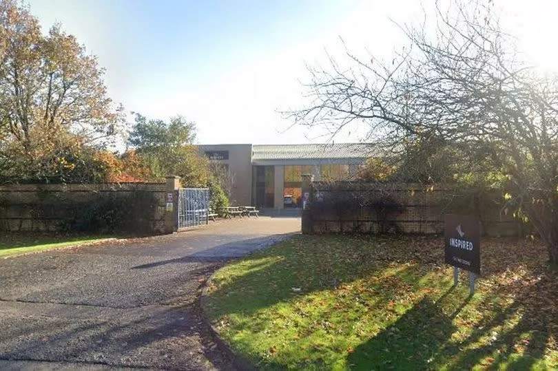 An external shot from the main road showing some of the factory behind gates