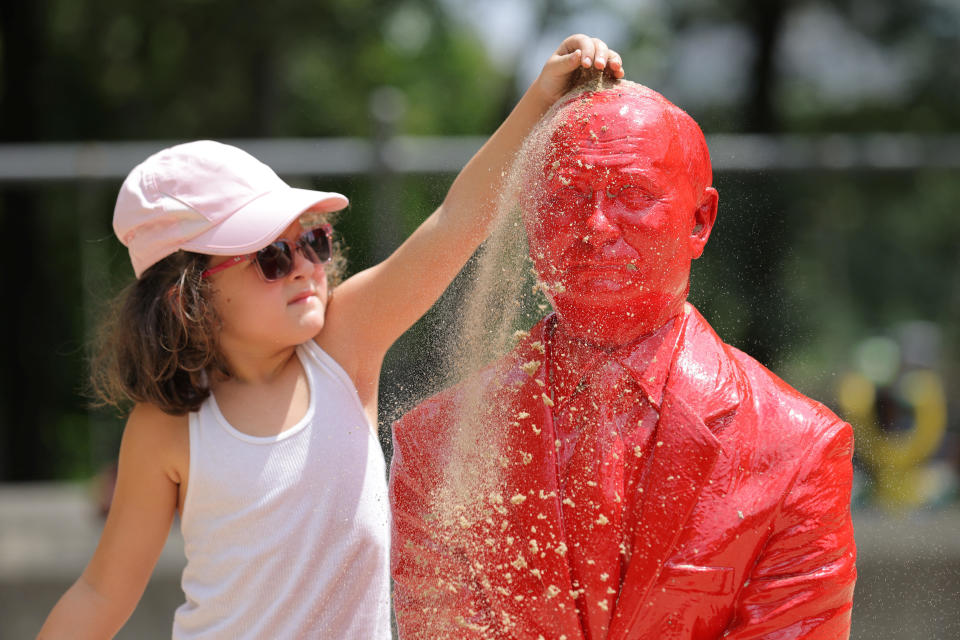 A child pours sand on a statue of Russian President Vladimir Putin riding a tank created by French artist James Colomina in Central Park in Manhattan, New York City, U.S., August 2, 2022. / Credit: ANDREW KELLY / REUTERS