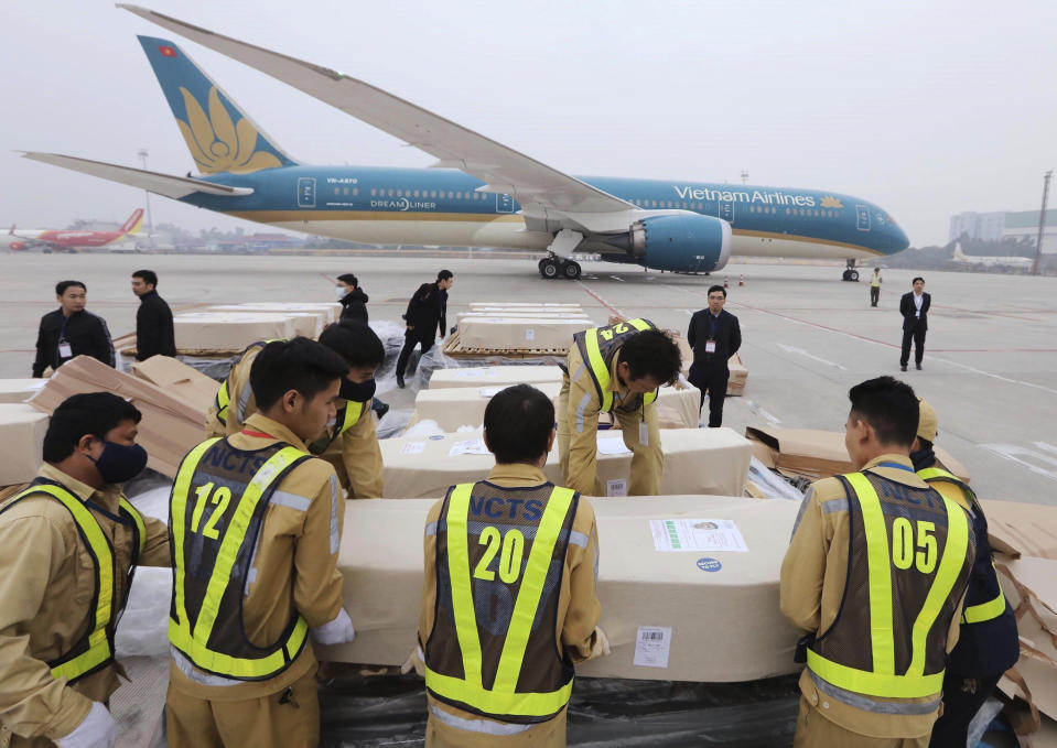Airport personnel line up a row of coffins on the tarmac of the Noi Bai airport in Hanoi, Vietnam, Saturday, Nov. 30, 2019. The last remains of the 39 Vietnamese who died while being smuggled in a truck to England last month have been repatriated to their home country. (Lam Khanh/VNA via AP)