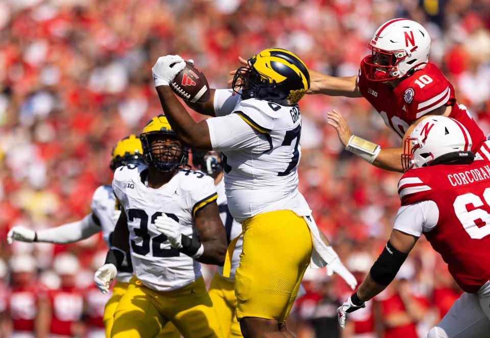 Michigan's Kenneth Grant, center, intercepts a deflected pass from Nebraska quarterback Heinrich Haarberg, top right, during the first half of an NCAA college football game Saturday, Sept. 30, 2023, in Lincoln, Neb.