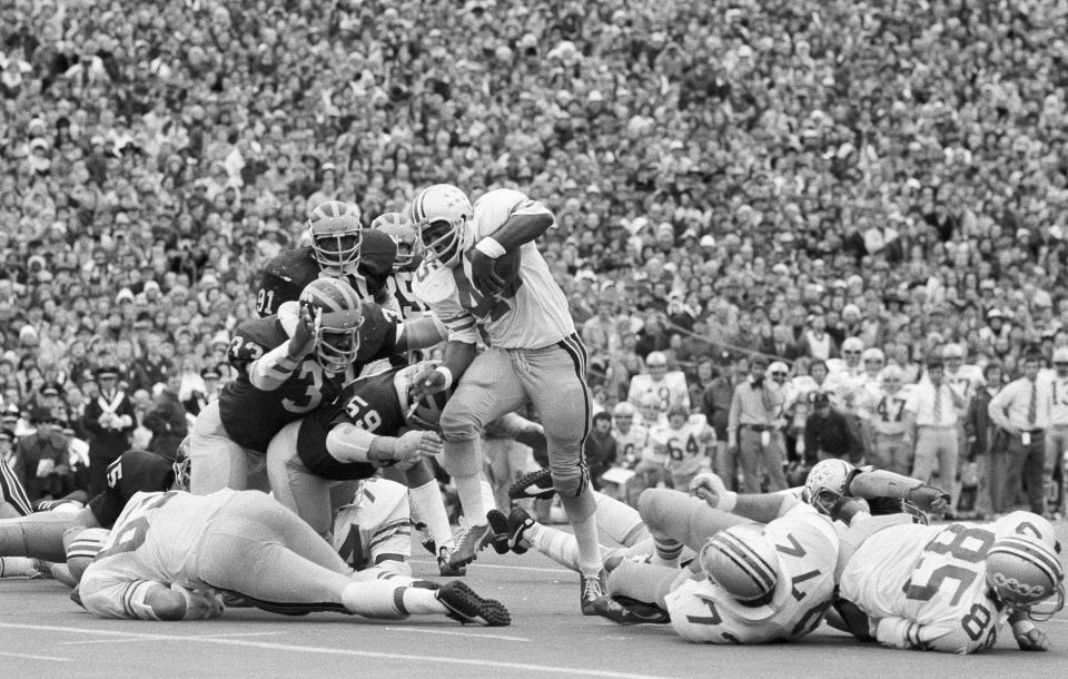 FILE - Ohio State's Archie Griffin picks up some of his game-high 163 yards against Michigan during an NCAA college football game in Ann Arbor, Mich., as Michigan's Walt Williamson (91), Carl Russ (33) and Steve Strinko (59) defend. The game between the undefeated teams ended in a 10-10 ties. (AP Photo, File)