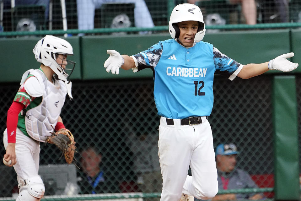 Curacao's Sean Serverie (12) gestures a he heads to first base after being walked with the bases loaded, while Mexico catcher Alfredo Chacon walks to the mound during the sixth inning of a baseball game at the Little League World Series in South Williamsport, Pa., Thursday, Aug. 24, 2023. (AP Photo/Tom E. Puskar)