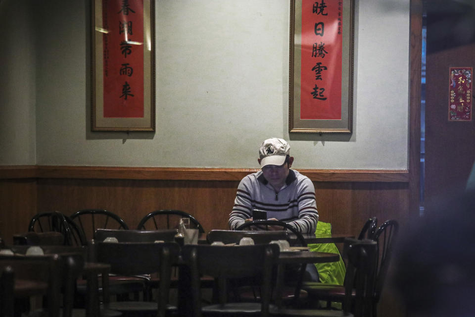 In this Feb. 13, 2020, photo, Frankie Chu, owner of Vegetarian Dim Sum House in New York's Chinatown, sits in his empty restaurant usually bustling with customers, in New York. Sales have plunged 70% over the last two weeks, "I don't know how long I can stay here," Chu said. "After 9/11, it wasn't this bad." (AP Photo/Bebeto Matthews)