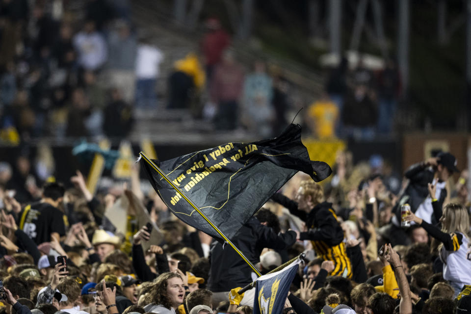 Fans wave a flag on the field after Appalachian State upset Coastal Carolina 30-27 in an NCAA college football game Wednesday, Oct. 20, 2021, in Boone, N.C. (AP Photo/Matt Kelley)