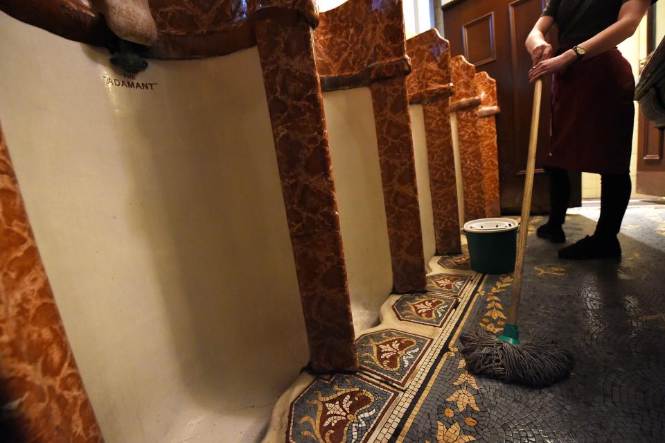 <p>A worker at the ornate men’s toilets in the Philharmonic dining rooms in Liverpool, England. (Photo: Paul Ellis/AFP/Getty Images) </p>