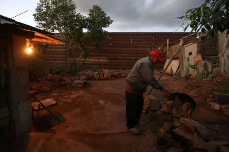 Pensioner Pedro, 72, caresses his dog Orejona outside his home near a section of the fence separating Mexico and the United States, on the outskirts of Tijuana, Mexico. REUTERS/Edgard Garrido