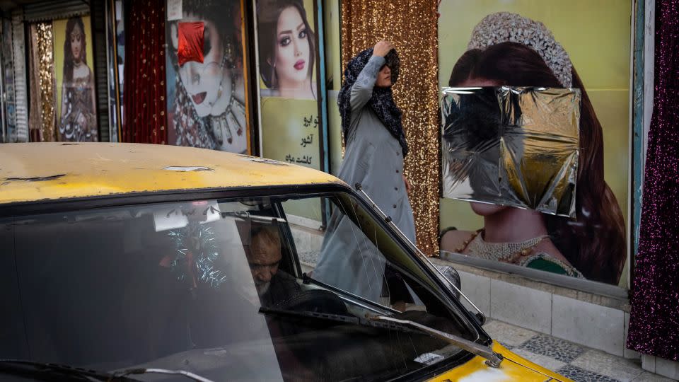 An Afghan woman walks past beauty salons with defaced window decorations, in Kabul, Afghanistan, on Sunday, Sept. 12, 2021. - Bernat Armangue/AP/File
