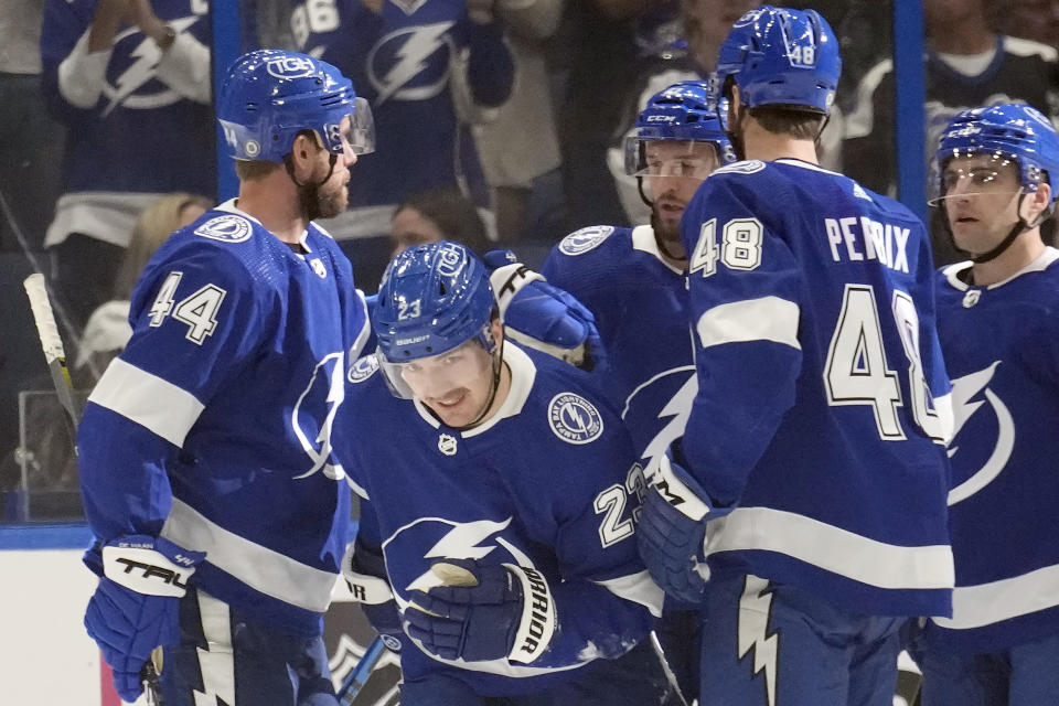 Tampa Bay Lightning center Michael Eyssimont (23) celebrates with teammates, including defenseman Nick Perbix (48) and defenseman Calvin de Haan (44) after scoring against the San Jose Sharks during the first period of an NHL hockey game Thursday, Oct. 26, 2023, in Tampa, Fla. (AP Photo/Chris O'Meara)